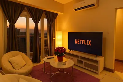 a living room with a television and a chair and a table at Elegant 1BR near Solaire, Okada, Mall of Asia in Manila