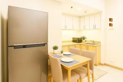 a small kitchen with a table and a refrigerator at Cozy 1BR near Solaire, Okada, Mall of Asia in Manila