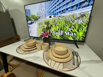 a table with plates and hats on it with a tv at Shore 2 Residences Room 360 POOL VIEW by Prime Stay MOA in Manila
