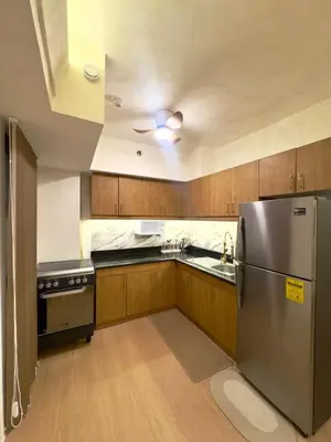 a kitchen with wooden cabinets and a stainless steel refrigerator at Taguig, near BGC Staycation in Manila
