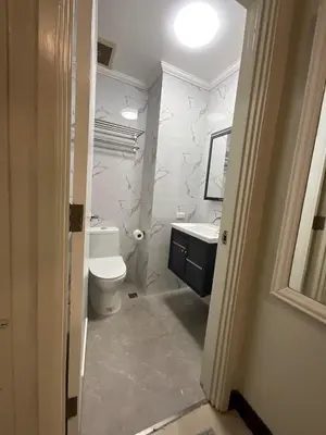a white bathroom with a toilet and a sink at Stunning flat in Alabang in Manila