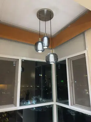 a window with three lights and a view of the city at Stunning flat in Alabang in Manila