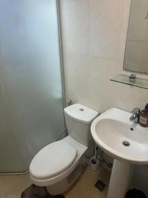a bathroom with a white toilet and a sink at Cozy Avant BGC 1Br Sleeps 4 in Manila