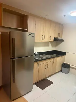 a kitchen with a stainless steel refrigerator and wooden cabinets at Cozy Avant BGC 1Br Sleeps 4 in Manila