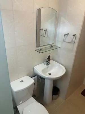 a bathroom with a toilet and a sink and a mirror at Cozy Avant BGC 1Br Sleeps 4 in Manila
