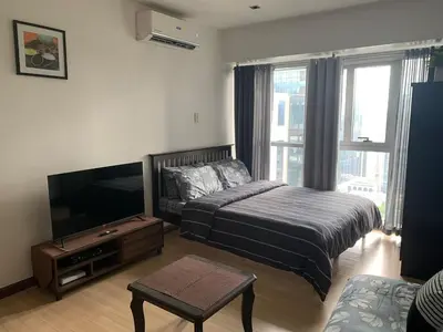 a bedroom with a bed and a flat screen tv at Furnished Studio in Knightsbridge Residences in Manila