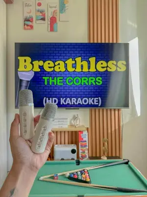 a person holding two microphones in front of a pool table at The Sandscape Suite in Manila