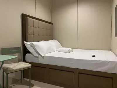 a bed with white sheets and a chair in a room at BuenaSentro Hostel in Manila