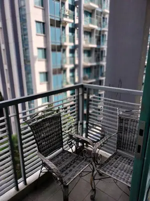 two chairs on a balcony with a view of a building at Rooms Near Airport-Rqui in Manila