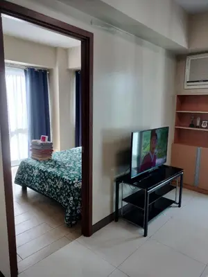 a living room with a tv and a bed and a mirror at Rooms Near Airport-Rqui in Manila
