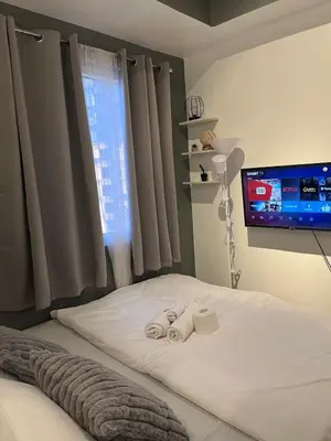 a bedroom with a bed with two rolled towels on it at Cozy Makati 2BR in CBD Ayala area with games, KTV, and Amazing Pools! in Manila