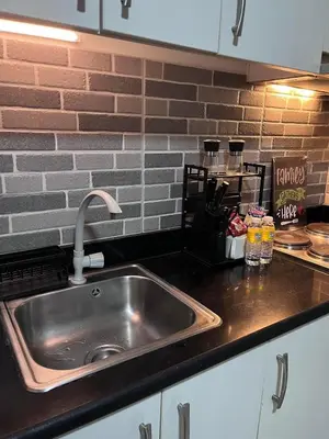 a kitchen counter with a stainless steel sink at Cozy Makati 2BR in CBD Ayala area with games, KTV, and Amazing Pools! in Manila