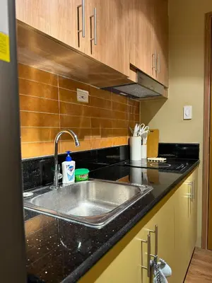 a kitchen with a stainless steel sink and wooden cabinets at Serenity Stays at Red Residences in Manila