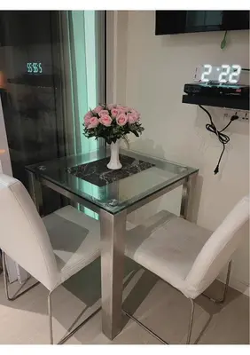 a glass table with two chairs and a vase with pink flowers at Azure Staycation by Leojen in Manila