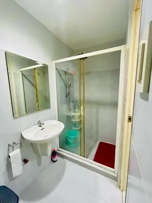 a white bathroom with a shower and a sink at Simple Staycay in Manila