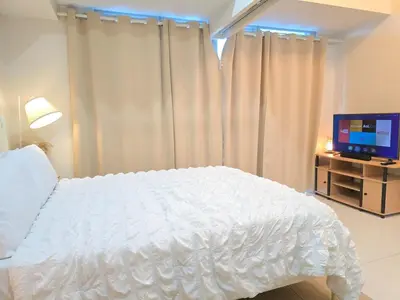 a bedroom with a white bed and a television at BGC Uptown Parksuites Cosy 1 Bedroom Suite with balcony 300MBPS wifi in Manila