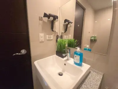a bathroom with a white sink and a mirror at BGC Uptown Parksuites Cosy 1 Bedroom Suite with balcony 300MBPS wifi in Manila