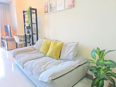 a white couch with yellow pillows in a living room at BGC Uptown Parksuites Cosy 1 Bedroom Suite with balcony 300MBPS wifi in Manila