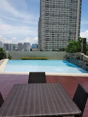 a table and chairs sitting next to a swimming pool at 1BR-unit in central BGC in Manila