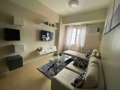 a living room with a couch and a tv at 1BR-unit in central BGC in Manila