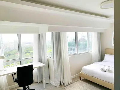 a bedroom with a bed and a desk and windows at 2BR Loft at Fort Victoria Condominium BGC in Manila