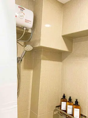 a shower in a bathroom with bottles on a shelf at 2BR Loft at Fort Victoria Condominium BGC in Manila