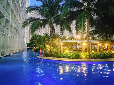 a hotel swimming pool with palm trees in front of a building at Azul Paradise in Manila