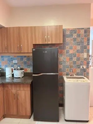 a kitchen with a black refrigerator and wooden cabinets at torre de manila taft luneta park view in Manila