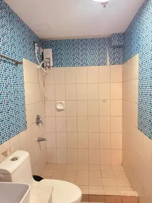 a bathroom with a toilet and a shower with blue tiles at torre de manila taft luneta park view in Manila
