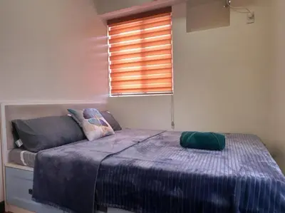 a bedroom with a bed with a blue blanket and a window at Family Rooms with View in Manila