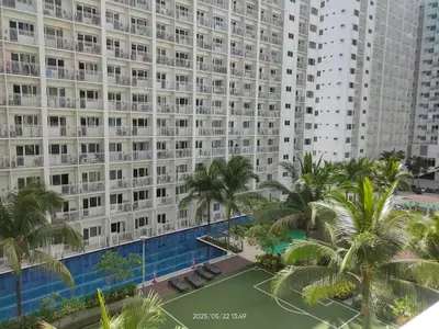 a large apartment building with a swimming pool and palm trees at Shore Residences in Manila