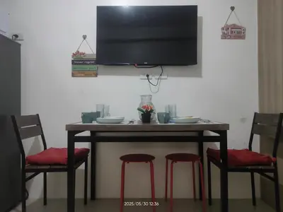 a table with red chairs and a television on a wall at Shore Residences in Manila