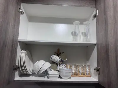 a cupboard with plates and bowls and vases at Coast Residences Ivy in Manila