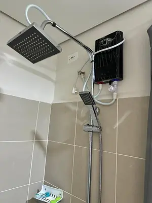 a bathroom with a shower with a laptop on the wall at Coast Residences Ivy in Manila