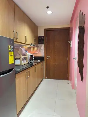 a kitchen with wooden cabinets and a pink door at 352B Shell Residences Barkada Room in Manila