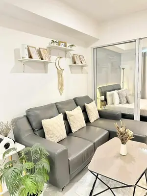 a living room with a leather couch and a bed at SM Bicutan Boracay Tower in Manila