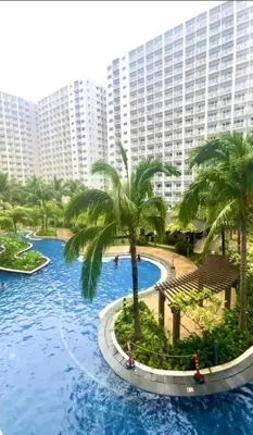 a large pool with palm trees in front of a large building at Manila Staycation walking distance to Mall of Asia and near Manila Airport in Manila