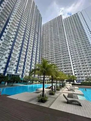 a large apartment building with a swimming pool and palm trees at Condotel or apartment SM JAZZ RESIDENCES in Manila