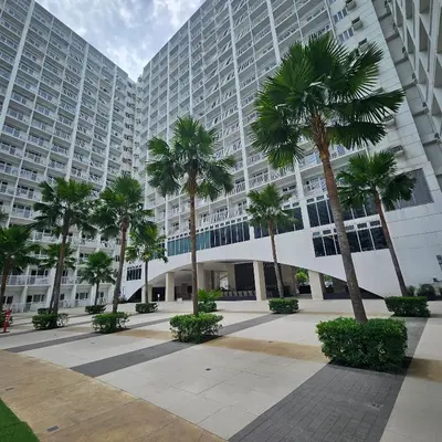 a large building with palm trees in front of it at Cathys Haven Urban Escape in MOA in Manila