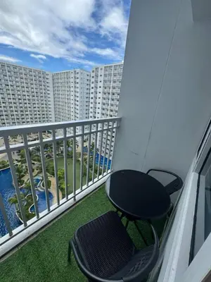 a table and a chair on a balcony with a building at Cathys Haven Urban Escape in MOA in Manila