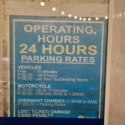 a sign for a hours parking rates at Cathys Haven Urban Escape in MOA in Manila