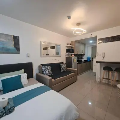 a bedroom with a bed and a couch and a kitchen at Cathys Haven Urban Escape in MOA in Manila