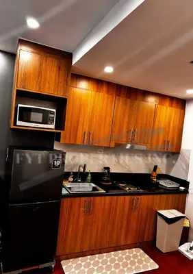 a kitchen with wooden cabinets and a black refrigerator at Modern Comfort at MOA Shore 3 in Manila