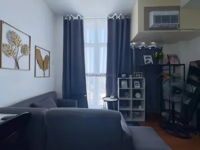 a living room with blue curtains and a couch at You Have VIN Here in Manila