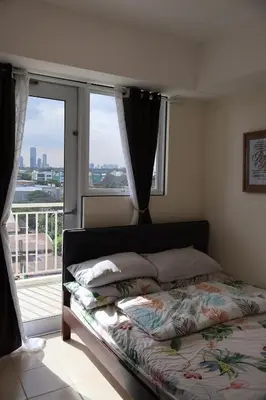 a bedroom with a bed and a window with a view at Kasara Urban Resort Elly's Pad with balcony in Manila
