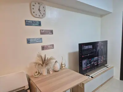 a living room with a tv and a clock on the wall at Kasara Urban Resort Elly's Pad with balcony in Manila