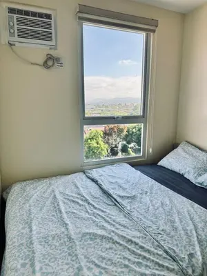 a bedroom with a bed and a large window at Danny's Haven Ortigas in Manila