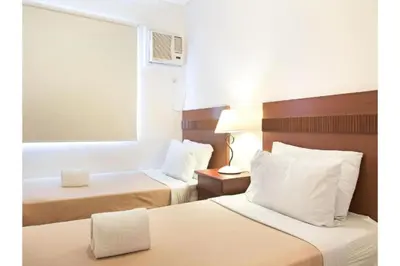 a hotel room with two beds and a mirror at Belvilla Airport Stays Near Makati Manila Formerly Avitel Hotel in Manila