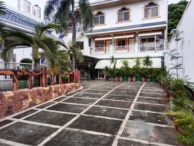 a courtyard in front of a building with palm trees at Your Little Resort, calm, secure in Manila