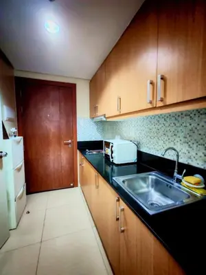 a kitchen with wooden cabinets and a sink and a refrigerator at Darren Staycation in Manila